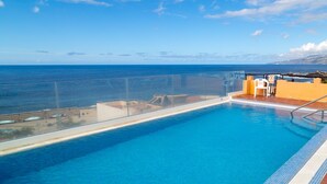 Una piscina con vista despejada al océano y un cielo soleado.
