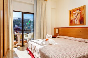 Habitación de hotel con una cama grande, un cuadro en la pared y vistas de la ciudad a través de la ventana.