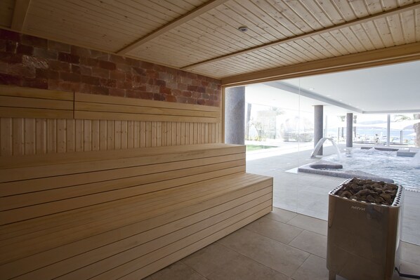 A wooden bench area with a stone wall and a view of an outdoor pool area. - Hotel Torre Del Mar (Ibiza Town)
