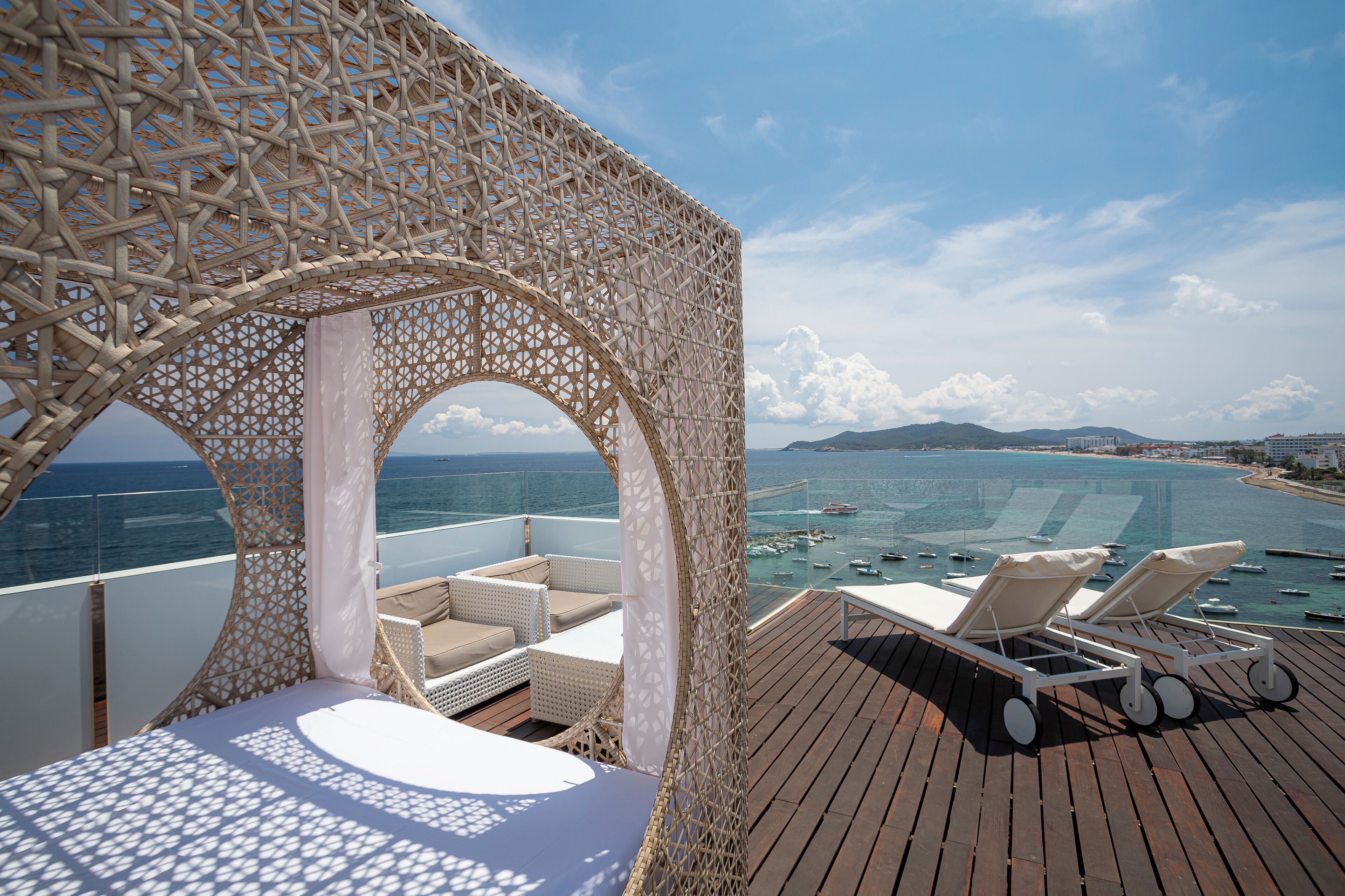 A sunlit deck with lounge chairs and a view of the sea.
