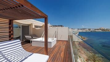 Eine Holzterrasse mit einem Bett, einer Badewanne und einer Liege.