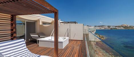 A wooden deck with a bed, a bathtub, and a lounge chair.