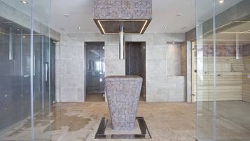Eine moderne Lobby mit einer zentralen Mosaik-Säule, Glaswänden und einem Fliesenboden.