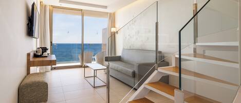 A modern hotel room with a glass staircase, a sofa, a small table, and a bench.
