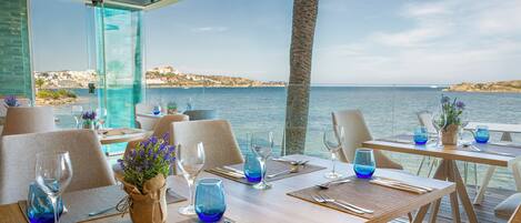 Un restaurante con mesas dispuestas para comer, con vista al mar.
