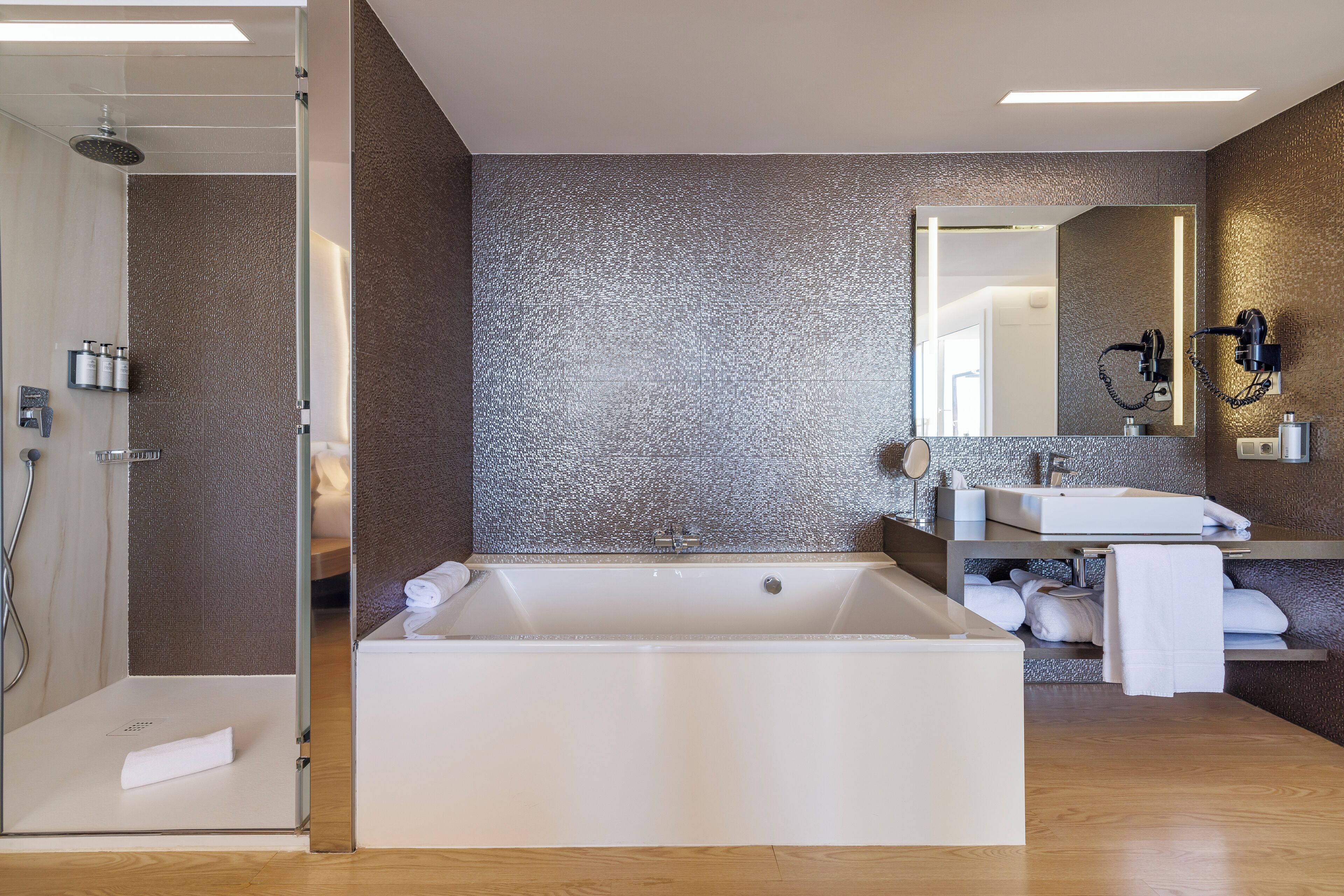 A modern bathroom with a large bathtub, a shower area, and a vanity with a mirror.