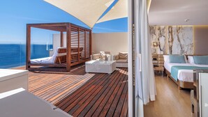 A balcony with a wooden floor, a seating area with a wooden canopy, and a bed with a marble wall. - Hotel Torre Del Mar (Ibiza Town)