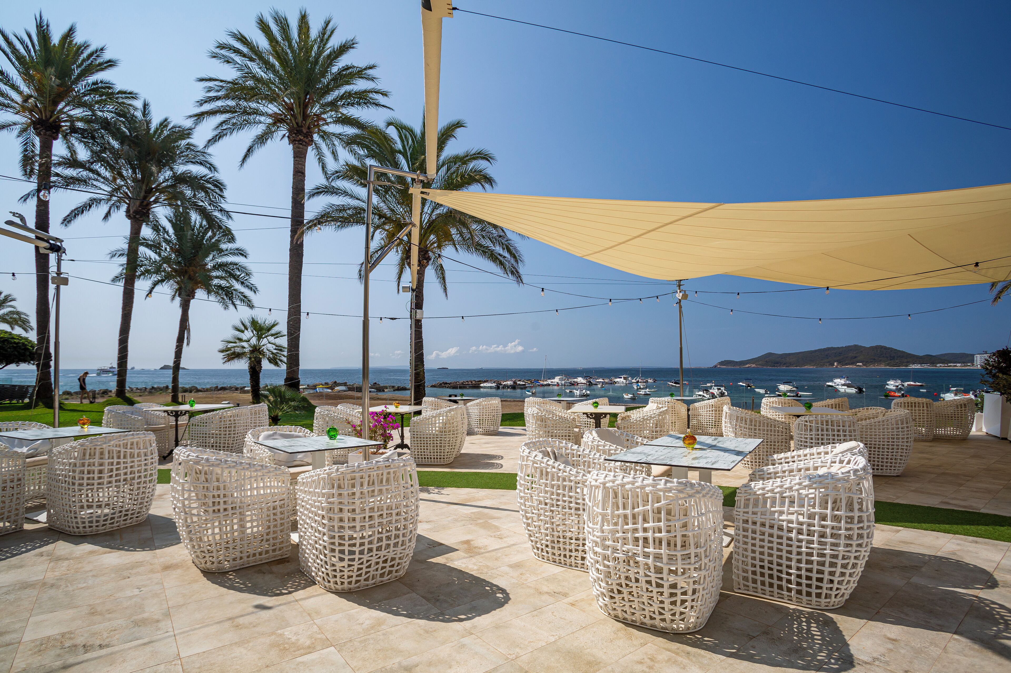 Outdoor seating with wicker furniture, a beach view, and a clear sky.