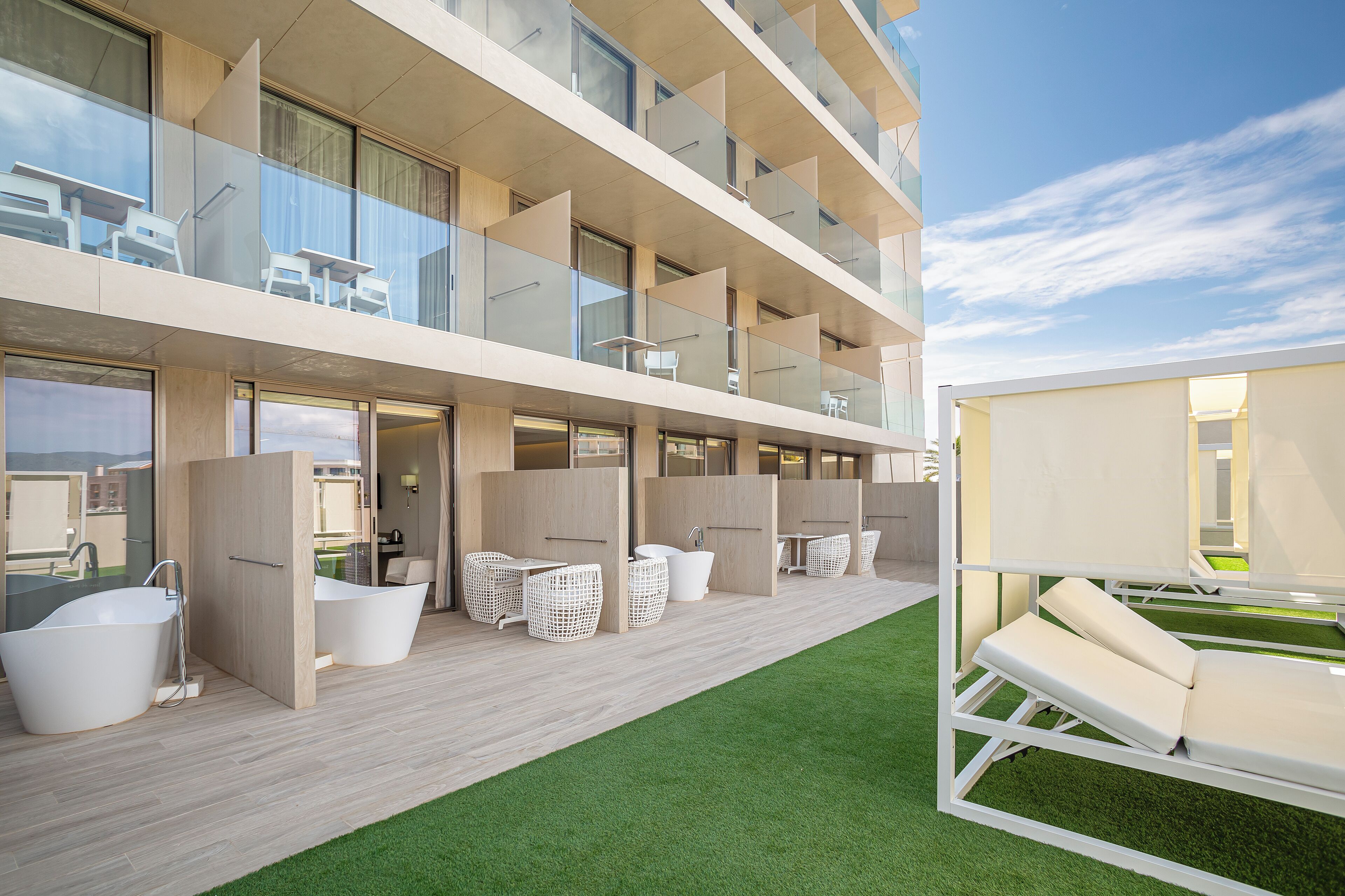 A modern hotel balcony with a pool area, including a jacuzzi, lounge chairs, and a sunbed.