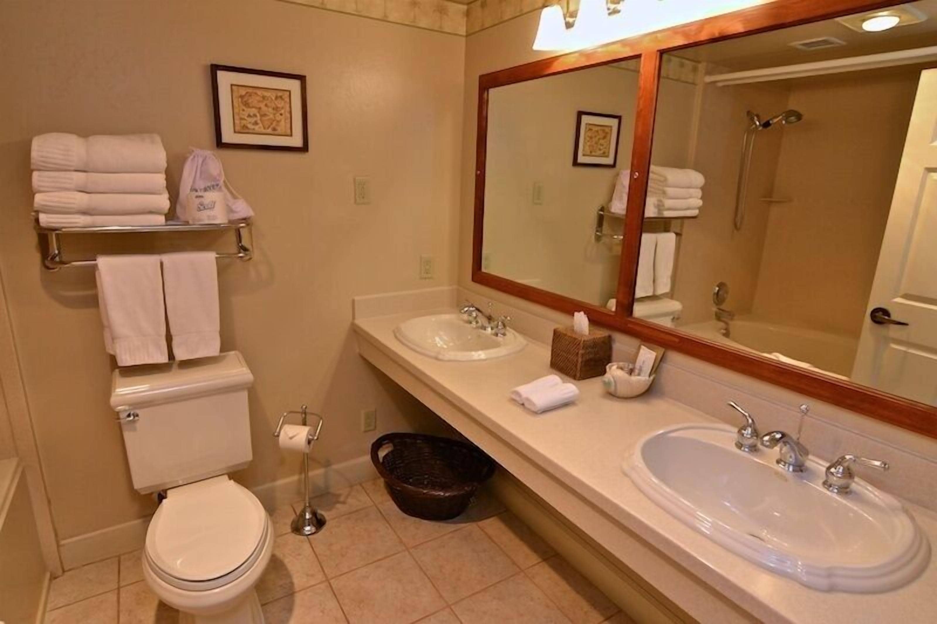 Un baño con inodoro, dos lavabos, un espejo grande y ducha.