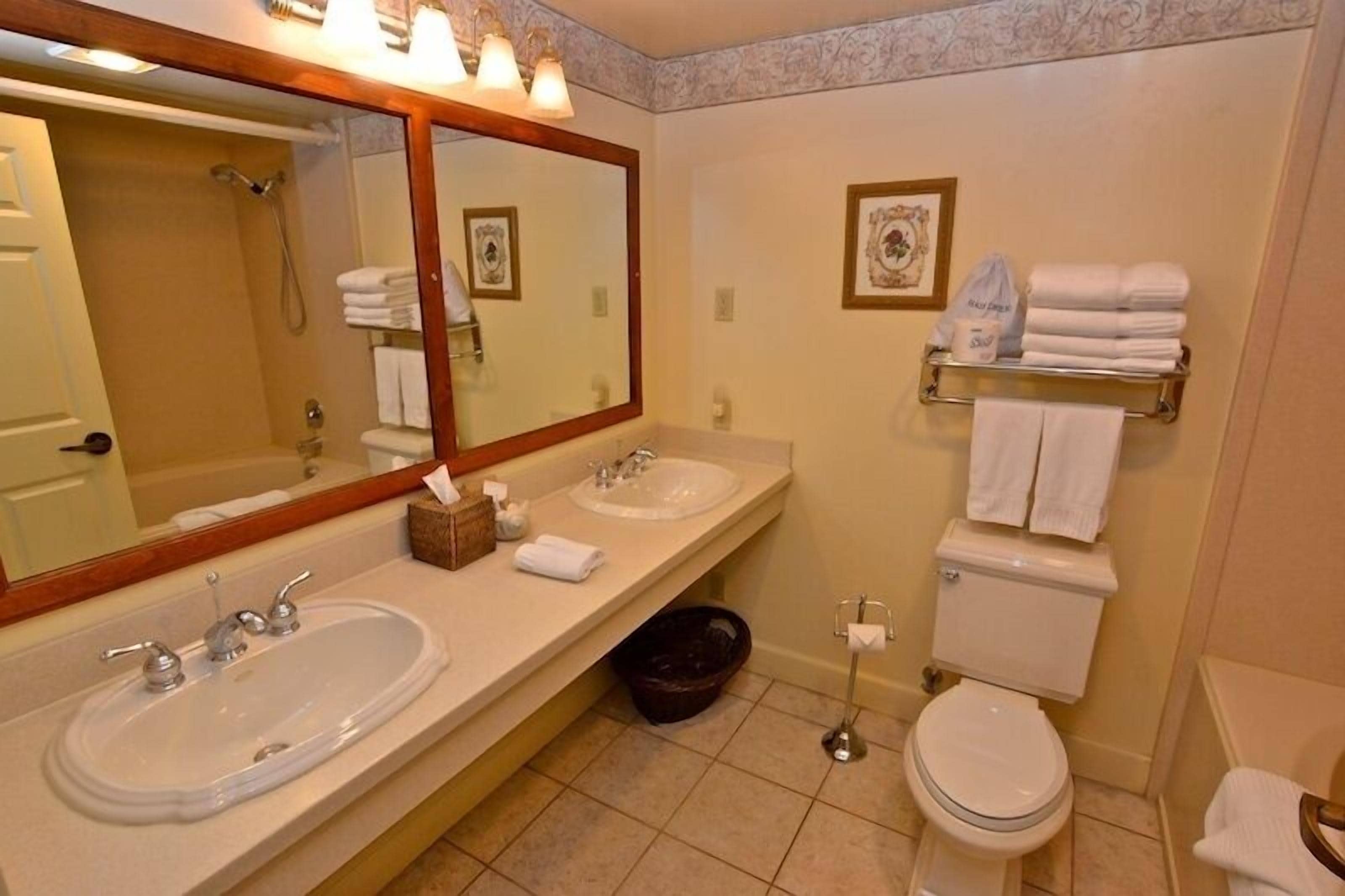 A bathroom with two sinks, a toilet, a shower, and a towel rack.