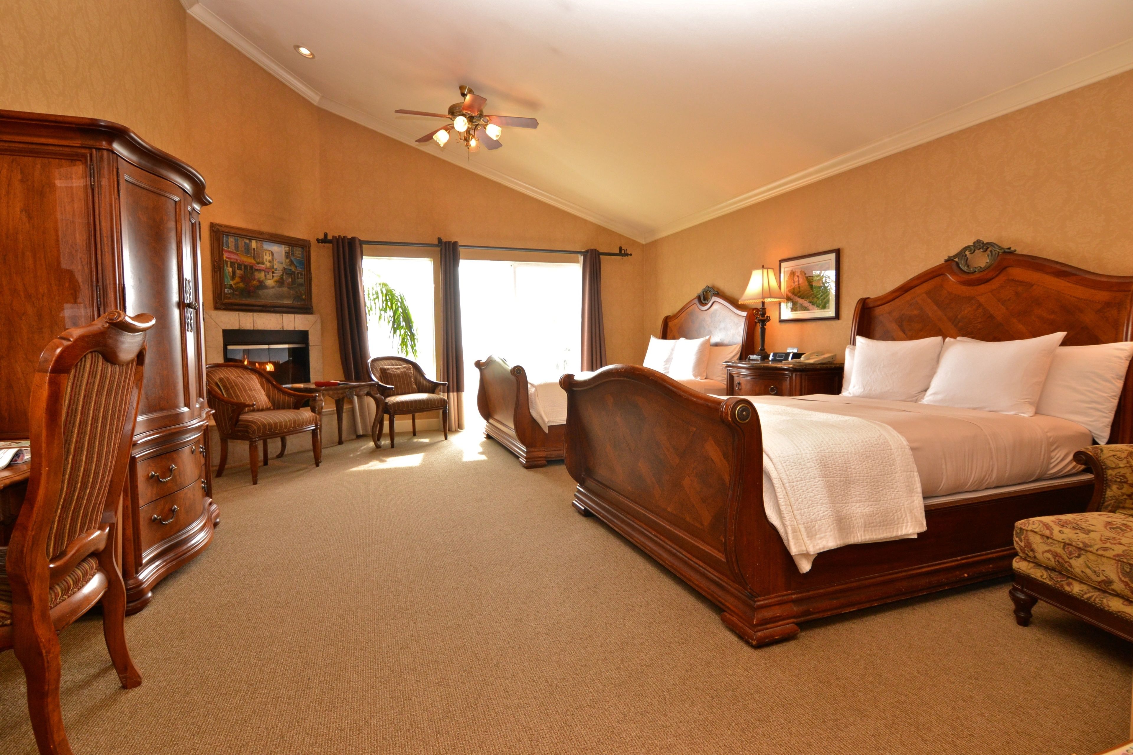 A spacious bedroom with a large bed, a wooden dresser, a desk, and a chair.
