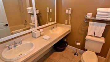 A bathroom with two sinks, a toilet, a shower, and a large mirror.