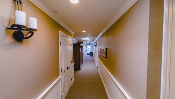 A hallway with a carpeted floor, white doors, and a wall-mounted light fixture with two candles.