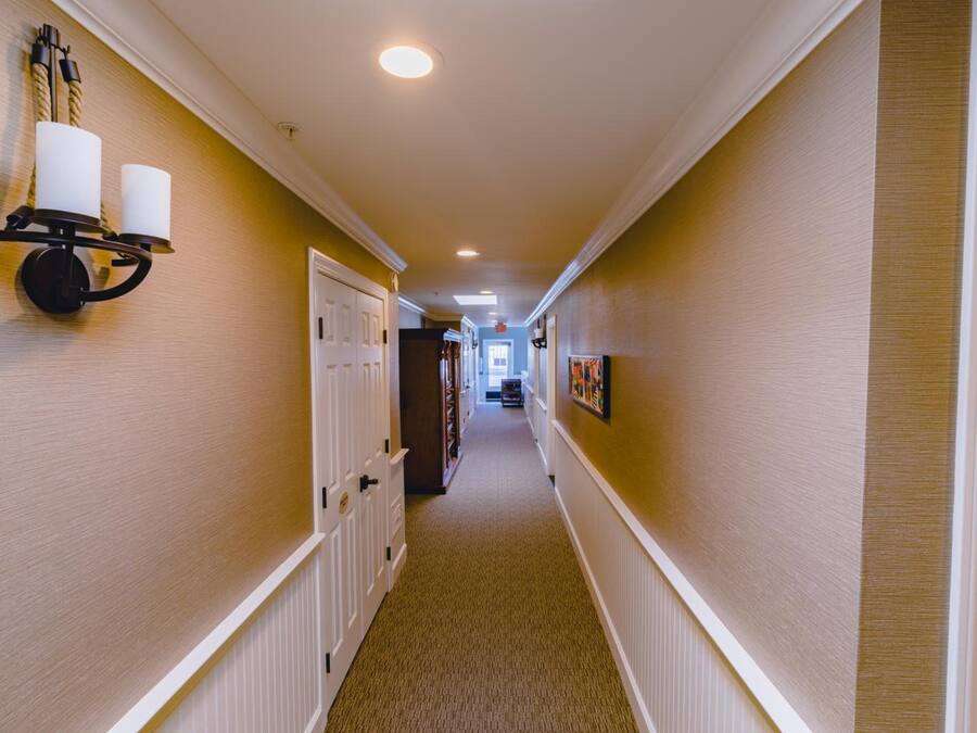 A hallway with a carpeted floor, white doors, and a wall-mounted light fixture with two candles.