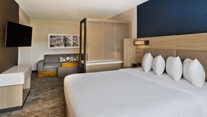 A hotel room with a large bed, a sofa, a desk, a TV, and a window with a view of the city. - SpringHill Suites by Marriott Birmingham Colonnade (Birmingham)