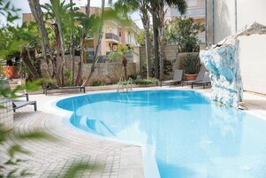 Una piscina al aire libre de temporada, sombrillas