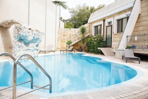 Una piscina al aire libre de temporada, sombrillas