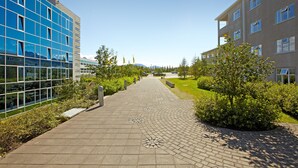 A paved walkway flanked by modern buildings with large windows and a clear sky. - Hotel Edda Akureyri (Akureyri)