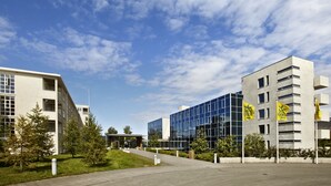A modern building with a glass facade, a flat roof, and a paved walkway leading to a building entrance. - Hotel Edda Akureyri (Akureyri)