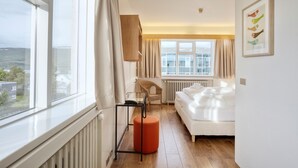 A bedroom with a large window, a bed, a chair, and a small table. - Hotel Edda Akureyri (Akureyri)