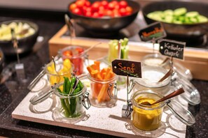 A buffet with various food items including vegetables, sauces, and a sign indicating 'Senf'.