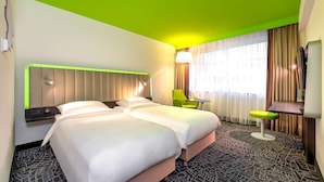 Habitació d'hotel amb dos llits, una taula de treball, una cadira i una televisió.