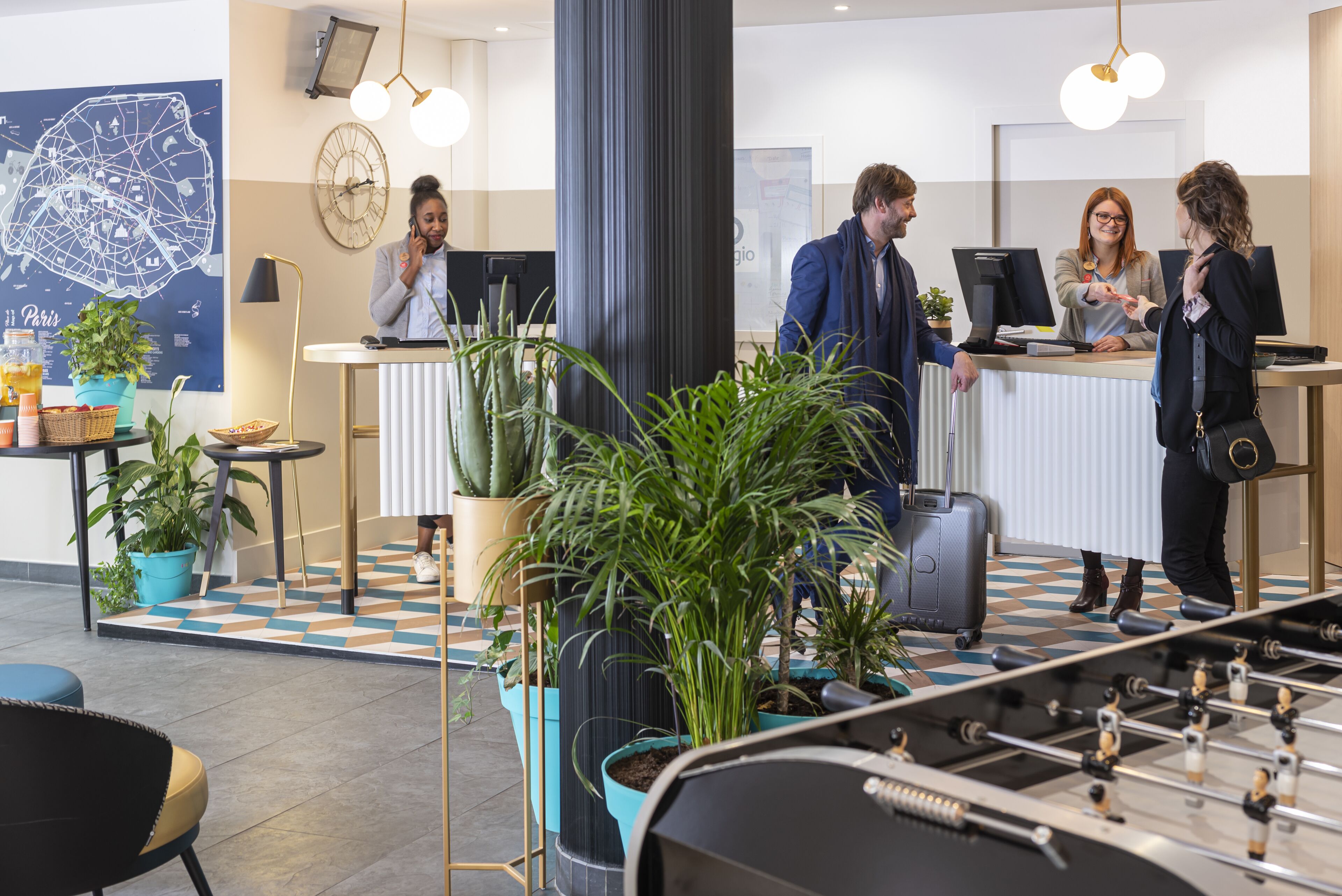 A lobby with a reception desk, a foosball table, and potted plants.