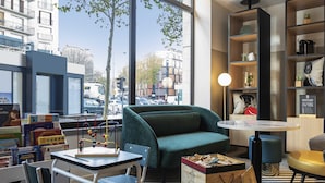 A modern interior with a green sofa, a striped floor, a table with chairs, and bookshelves.