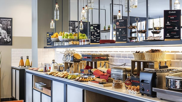 A breakfast buffet with various food items, a coffee machine, and hanging light fixtures.