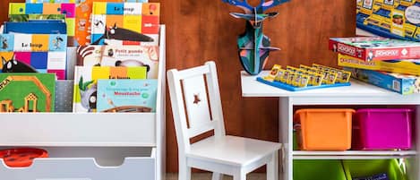 Habitación infantil con libros educativos, un juego de Monopoly y una decoración con cabeza de ciervo.