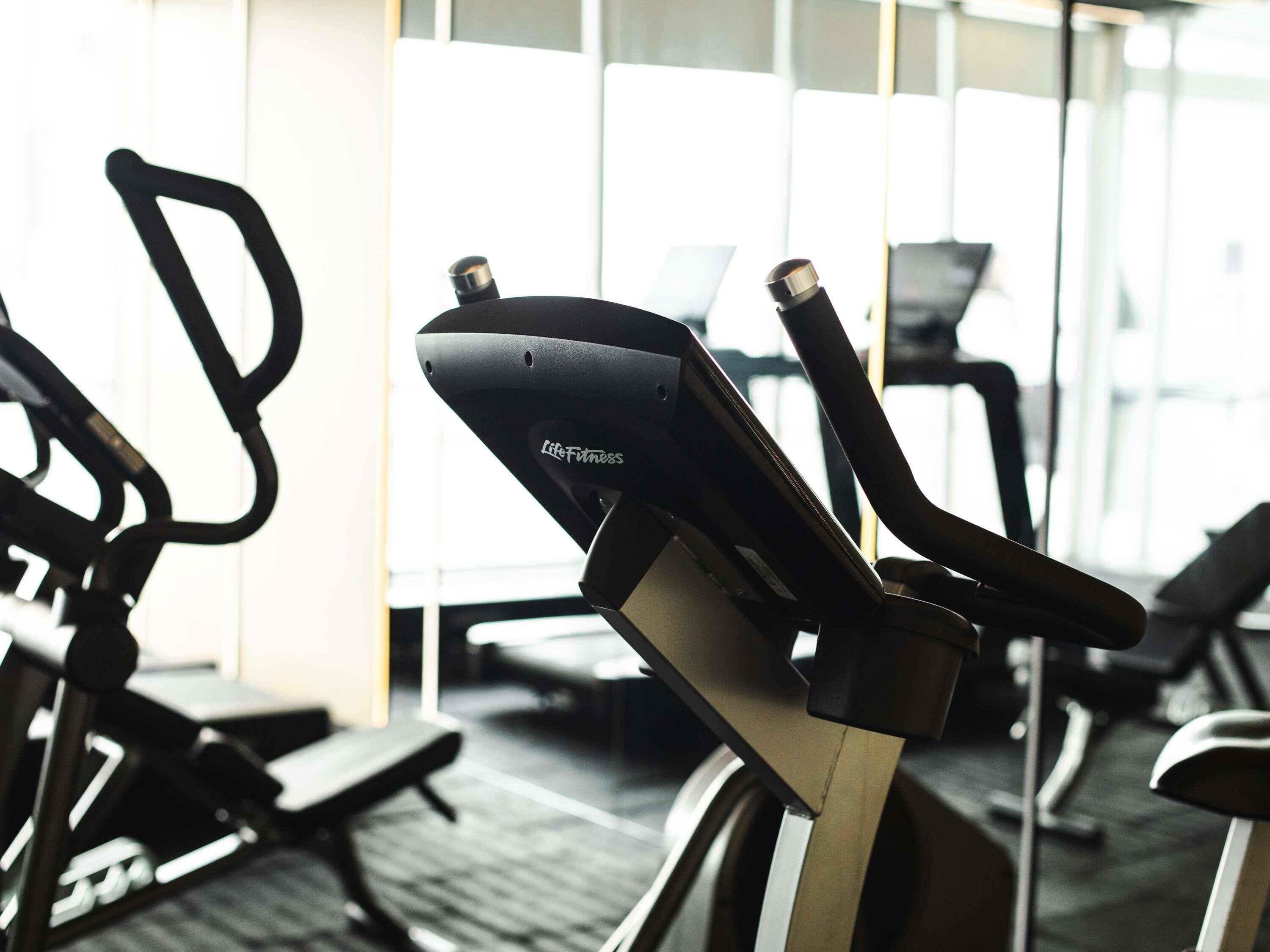 A stationary bike with a Life Fitness logo, a wall-mounted mirror, and a window with blinds.