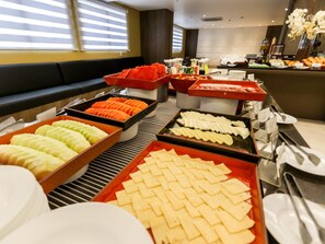 A buffet with various food items and a seating area with a sofa. - Mercure Camboriu Hotel (Balneário Camboriú)