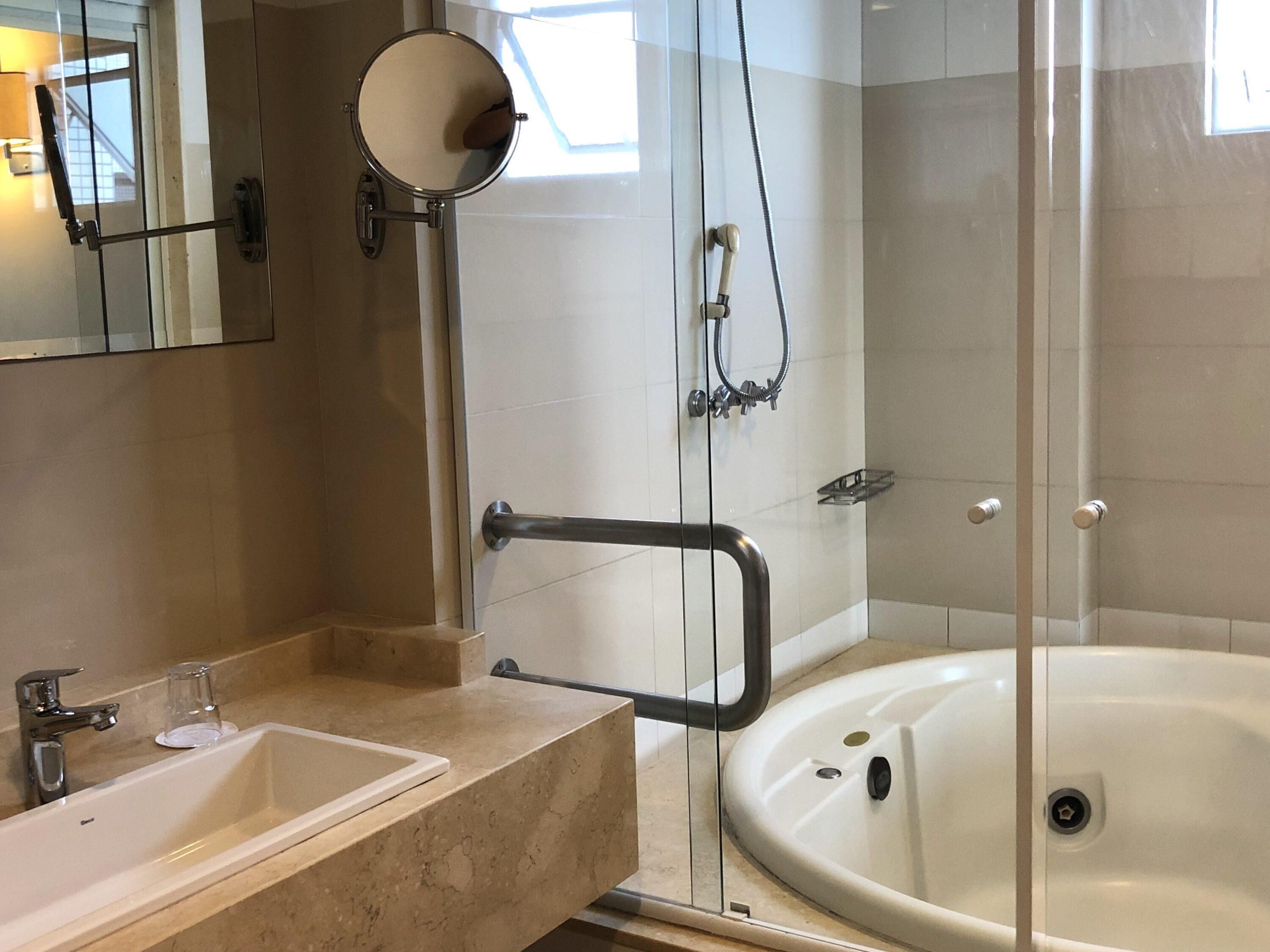 A bathroom with a bathtub, a sink, a mirror, and a shower area.