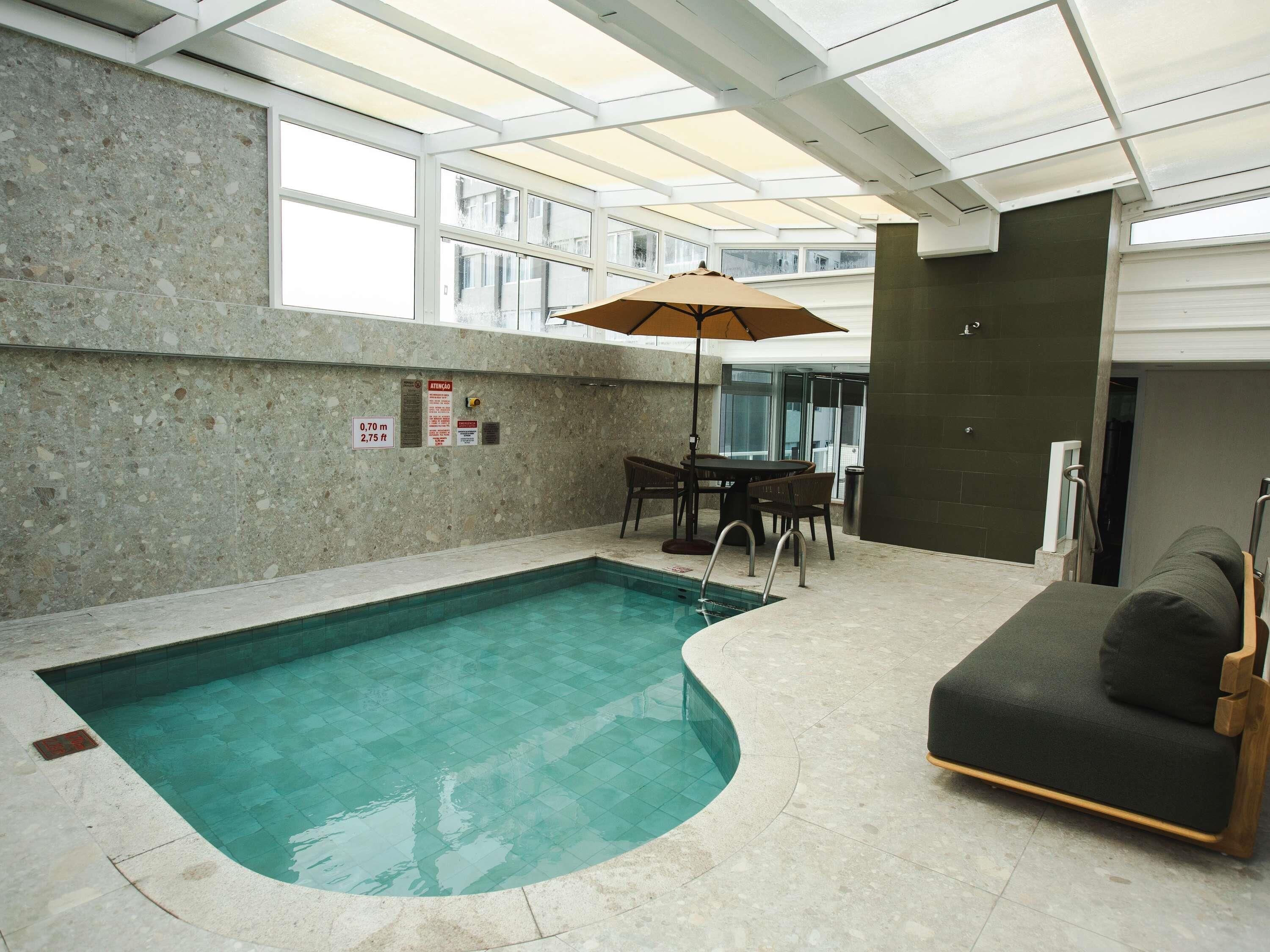 Ein Innenpool mit Glasdecke, einem Tisch mit Stühlen und einer Couch.