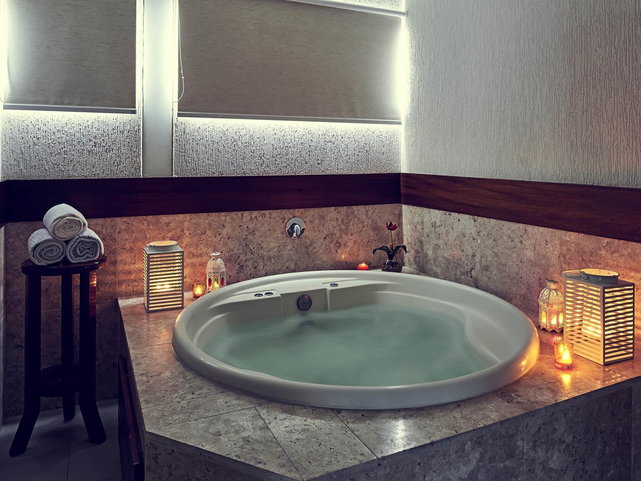A modern bathroom with a freestanding bathtub, a small table with towels, and decorative candles.