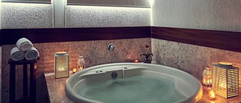 A modern bathroom with a freestanding bathtub, a small table with towels, and decorative candles.