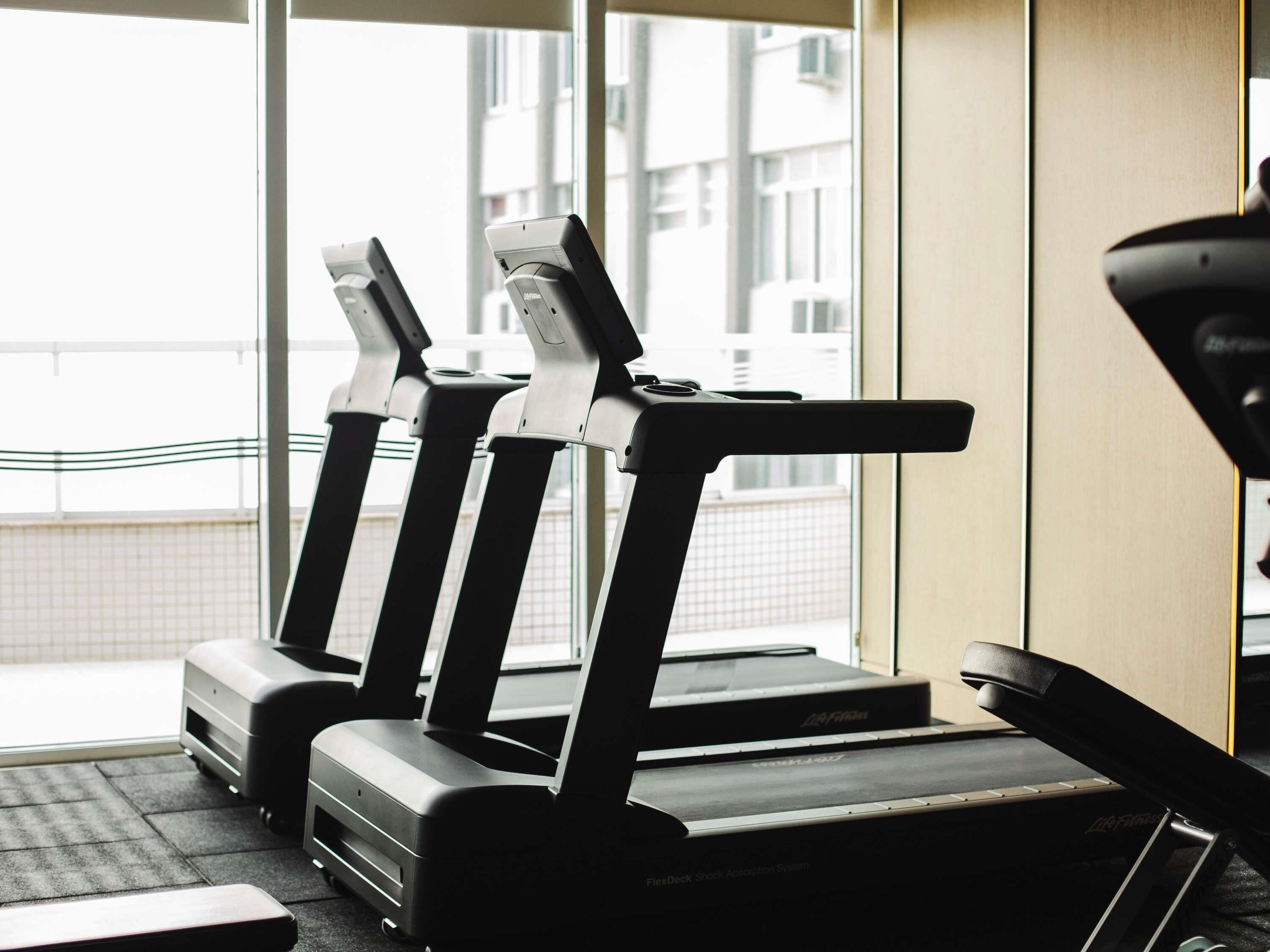 Un gimnasio con cintas de correr, una bicicleta estática y una máquina de remo.