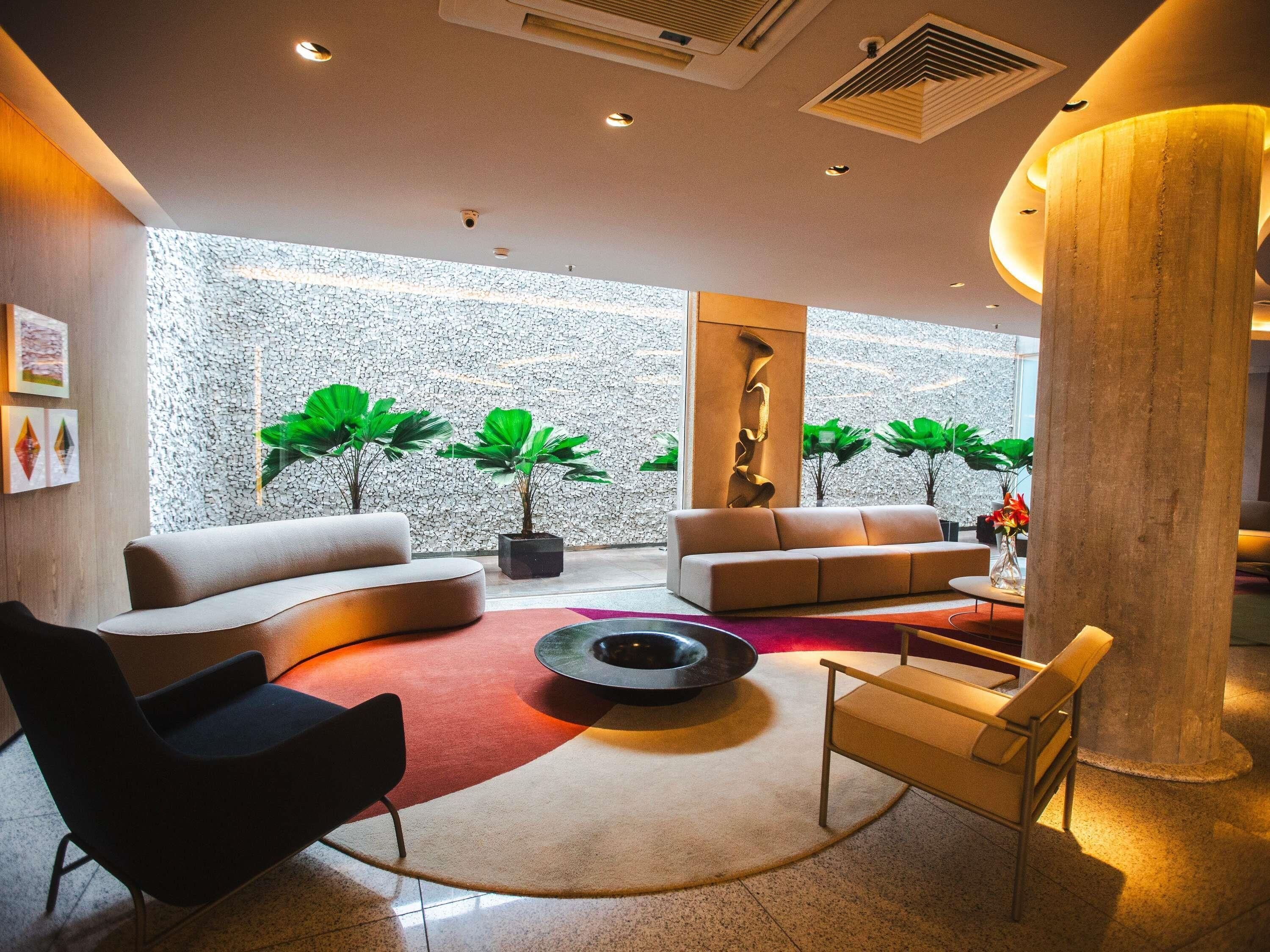 A modern interior with a curved sofa, a round coffee table, and potted plants.