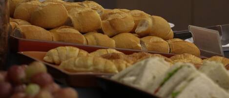 A buffet with various food items including sandwiches and pastries.