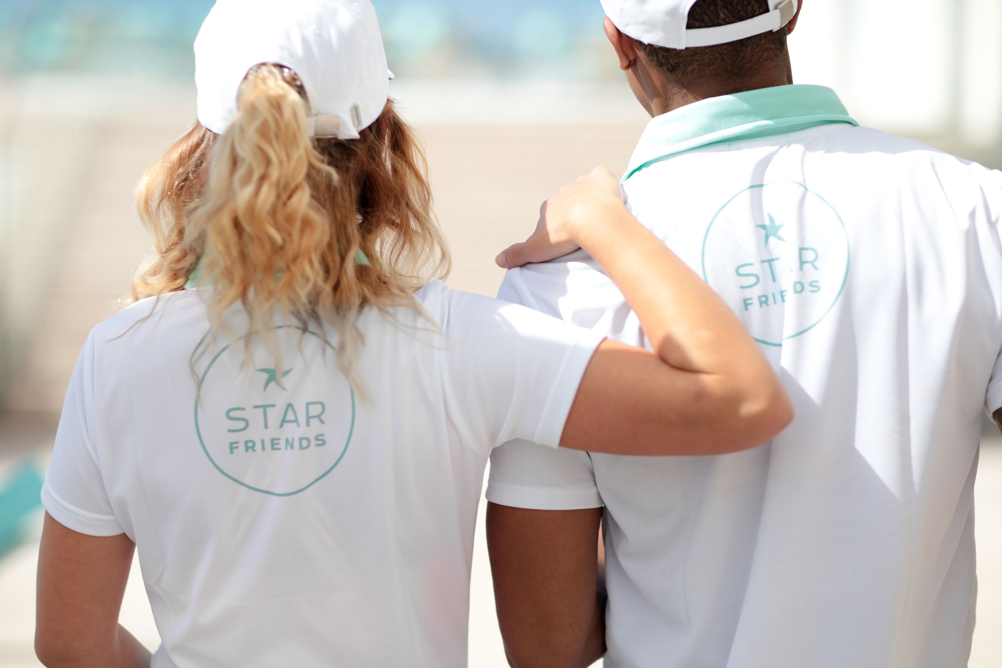 Two people wearing white t-shirts with "STAR FRIENDS" logo on the back.