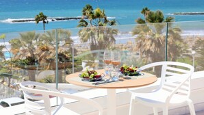 A table with two chairs, a glass of water, and a glass of wine, overlooking a beach with palm trees and the ocean. - Iberostar Selection Sábila - Adults Only (Adeje)