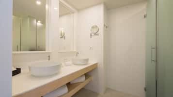 A modern bathroom with two sinks, a large mirror, and a glass shower enclosure.