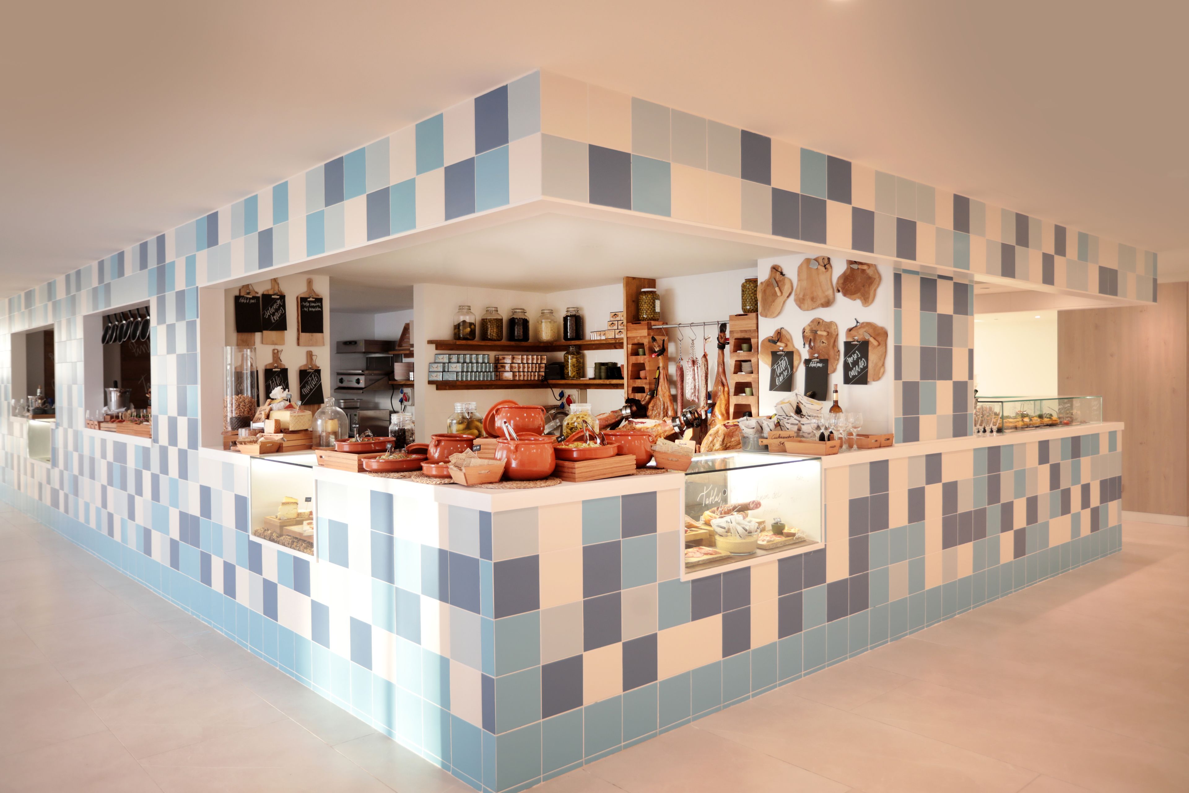 Una cocina moderna con salpicadero de azulejos a cuadros, repisas abiertas con utensilios de cocina y una isla central con instrumentos de cocina.