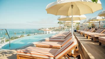Relax by the infinity pool surrounded by comfortable sun loungers and umbrellas.