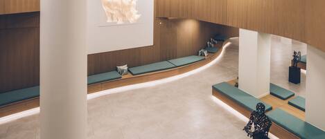 Una hall moderna con una reception a forma di curva, aree lounge e un'ampia scultura di un rinoceronte fissata alla parete.