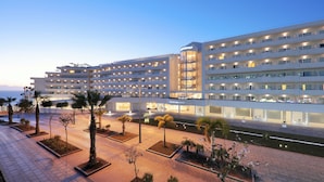 A multi-story hotel with a modern design, featuring a central courtyard with palm trees and a water feature. - Iberostar Selection Sábila - Adults Only (Adeje)