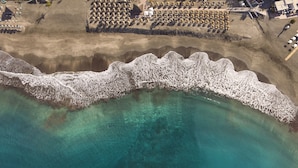An aerial view of a coastal area with a sandy beach and a rocky breakwater. - Iberostar Selection Sábila - Adults Only (Adeje)