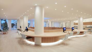 A spacious, modern reception area with a curved counter, multiple computer monitors, and a minimalist design.