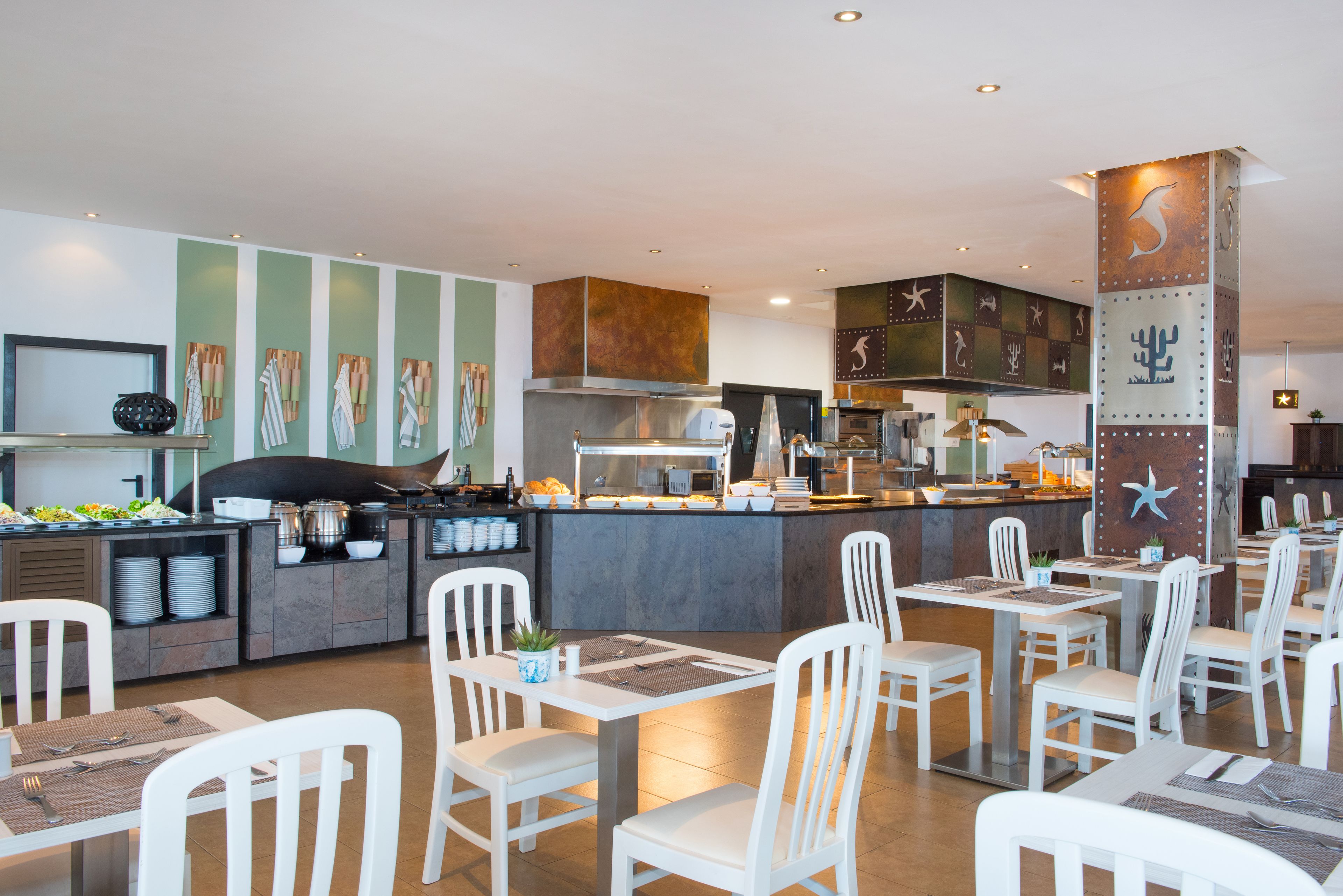 Un restaurante moderno con barra central, sillas blancas y zona de bufé.
